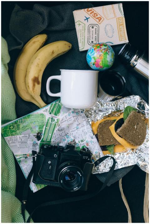 Flat lay of travel items including a map, camera,