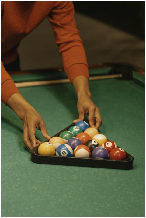 A close-up view of a person arranging billiard bal