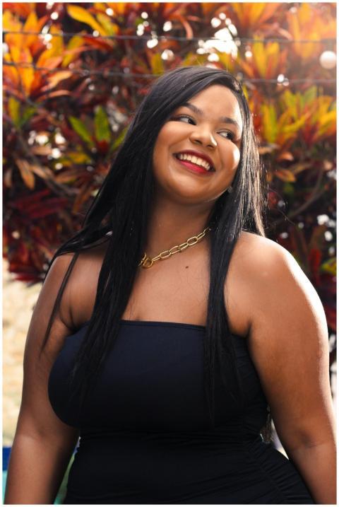 A joyful woman with long dark hair and a gold neck