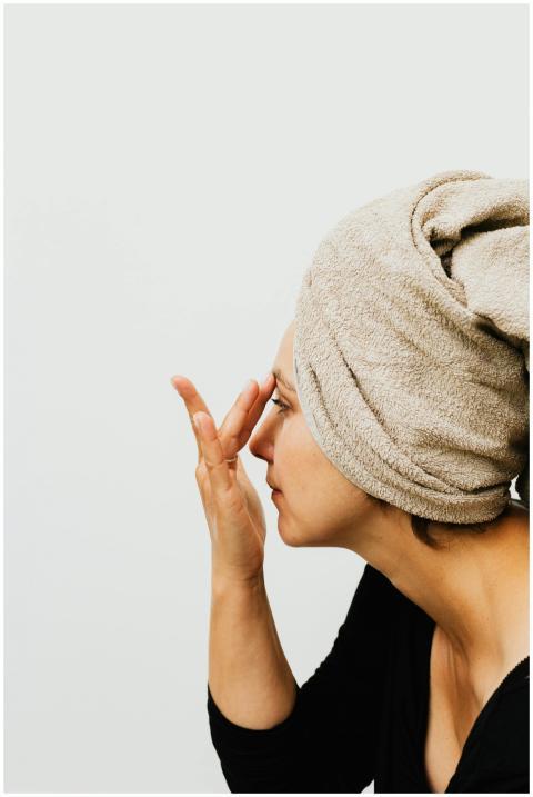 Side view of a woman applying skincare cream with