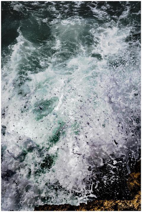 High angle shot of ocean waves crashing on rocky s