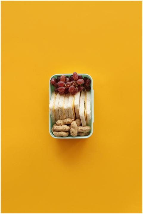Top view of a lunch box with grapes, sandwich, and
