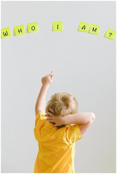 Blond child in yellow shirt pointing at words 'WHO