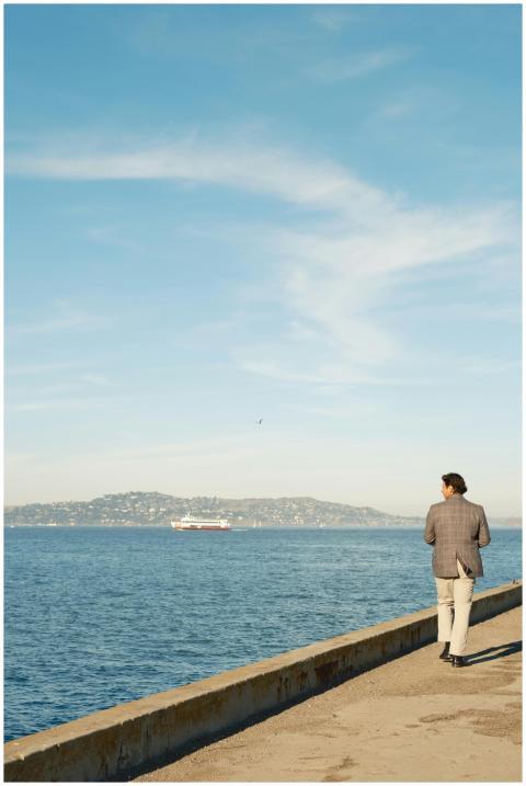 Elegant man walking by the ocean with distant hill