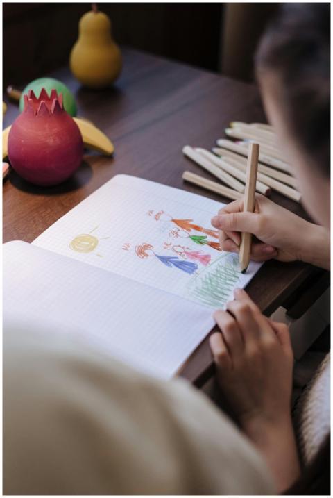 A child uses colored pencils to draw a family port