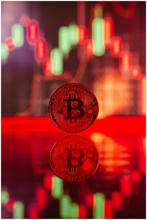 Red Bitcoin coin with reflection against digital t