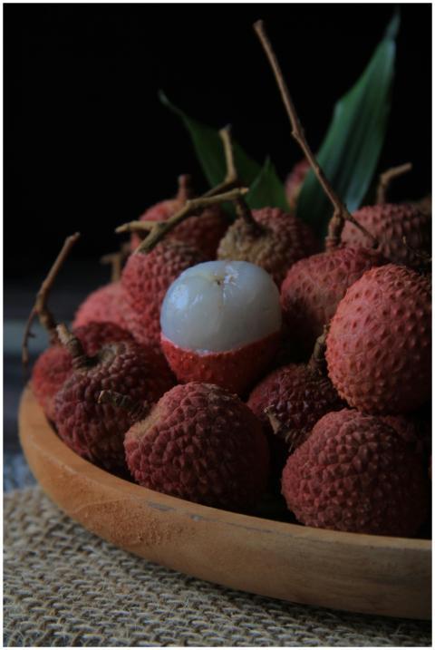 A close-up of fresh lychees with a peeled one in a