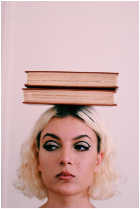Close-up of a woman balancing books on her head wi