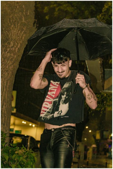 A stylish young man holding an umbrella in a rainy