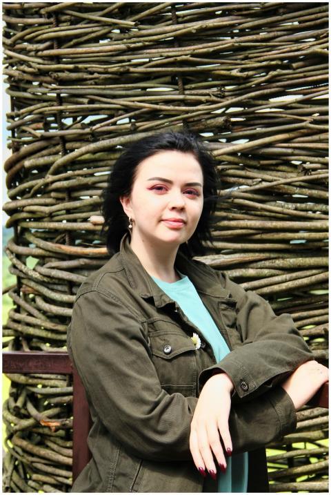 Young woman posing outdoors against a rustic woven
