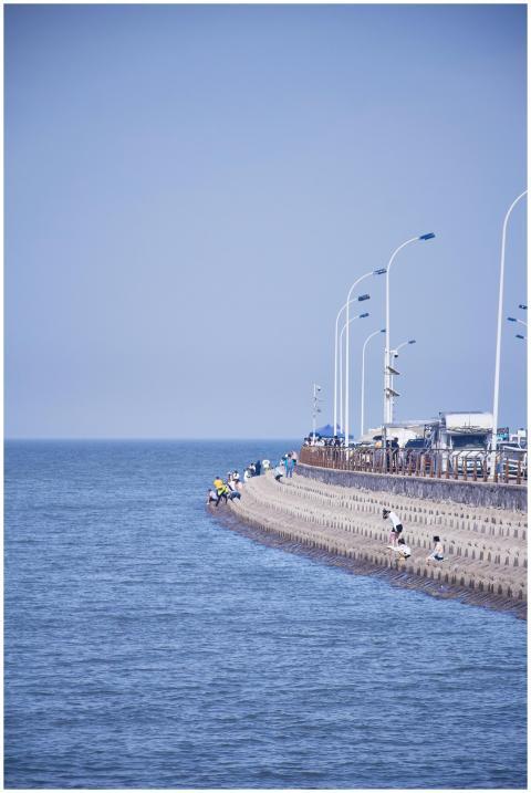 People enjoy a sunny day on a coastal promenade by