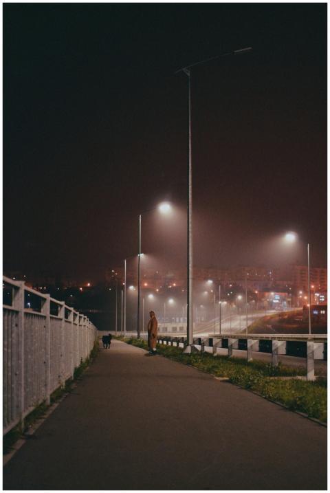 A lone pedestrian walks along a foggy city sidewal