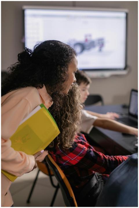 A woman assists students during a computer-based c