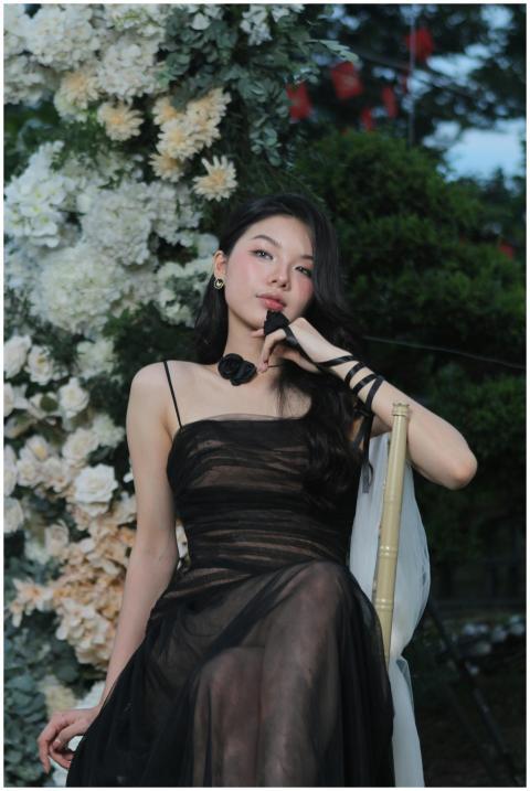 Elegant woman in black dress posing by floral back
