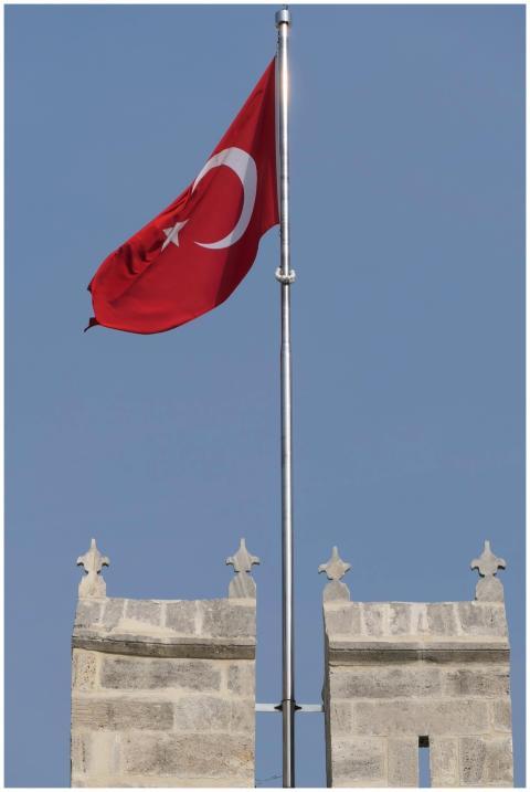 Turkish flag waving on a castle tower against a cl