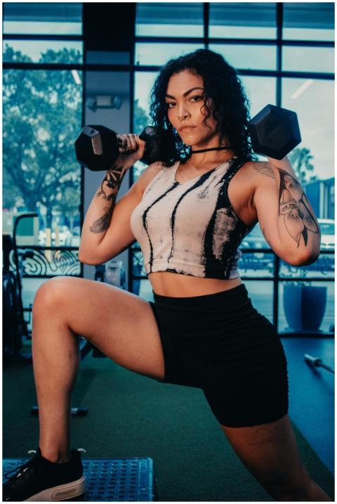 Empowering portrait of a woman exercising with dum