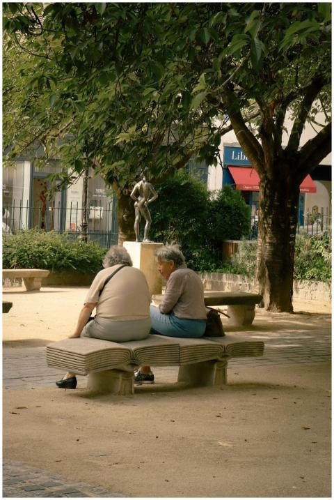 Two people relax on a bench in a Paris park, enjoy