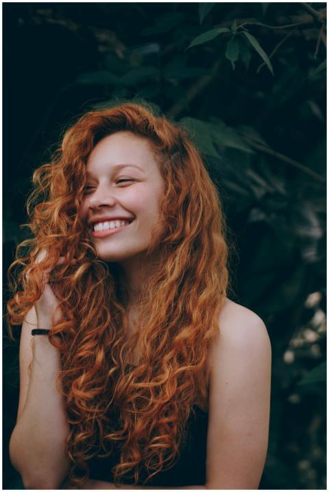 A candid portrait of a joyful woman with curly red
