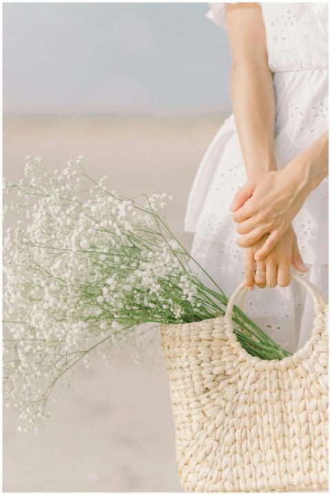 A woman in white holding a woven basket filled wit