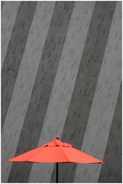 Bold red umbrella contrasts sharply with a geometr