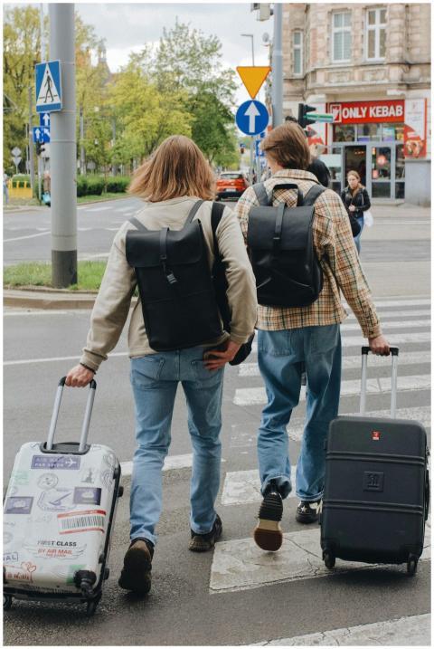 Two tourists crossing a street with suitcases in P