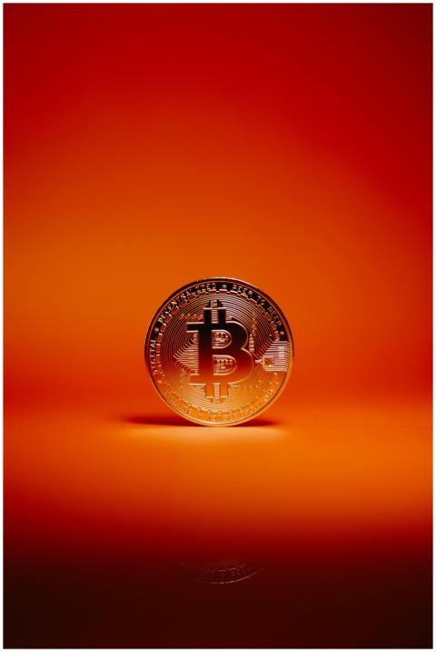 Close-up of a Bitcoin coin against a striking oran