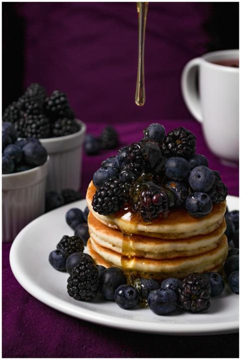 Stack of fluffy pancakes topped with fresh blackbe