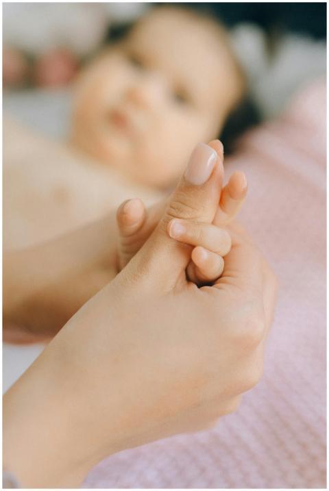A close-up of a mother gently holding her baby's h
