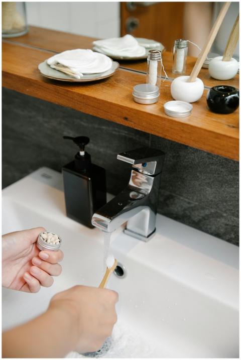 Hand applying natural toothpaste on a bamboo tooth