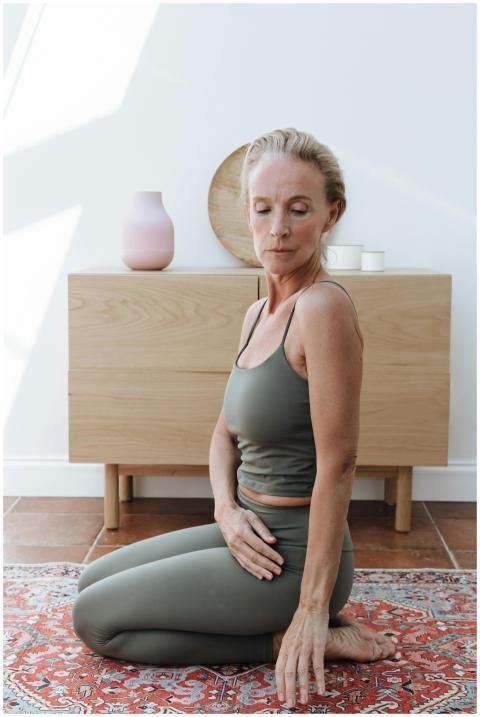 Senior woman practicing yoga indoors, embracing a