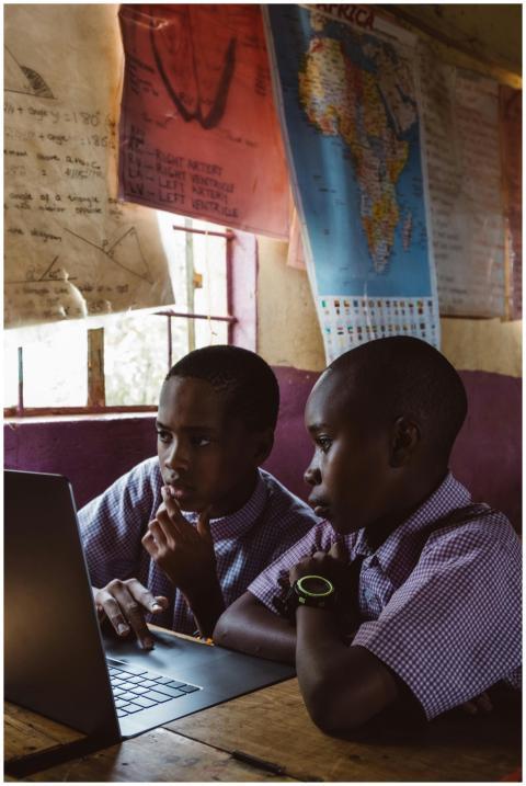 Two boys in school uniforms learning together on a