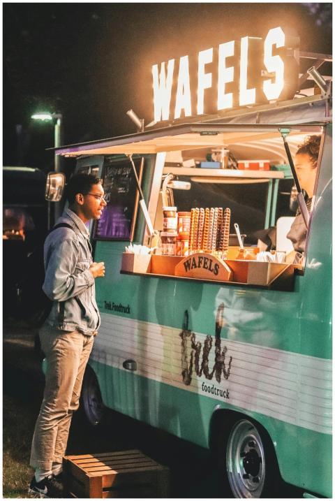A customer waits at a vibrant waffle food truck in