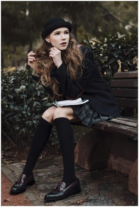 Stylish woman in dark academia attire seated on a