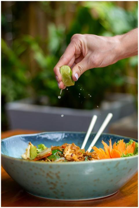 A hand squeezes fresh lime juice over a colorful s