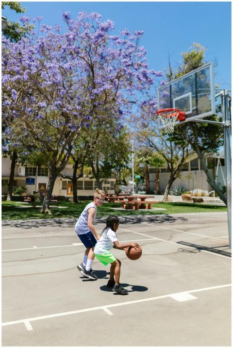 Two boys playing basketball on an outdoor court un