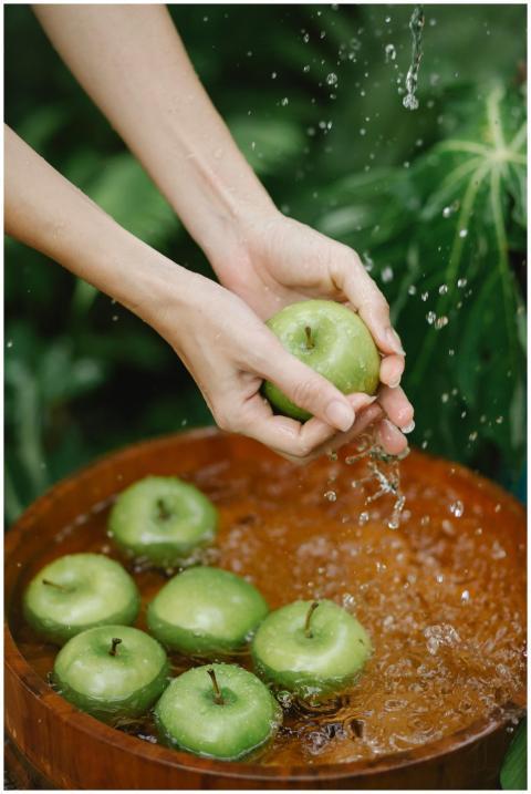 Hands wash fresh green apples in a wooden basin ou