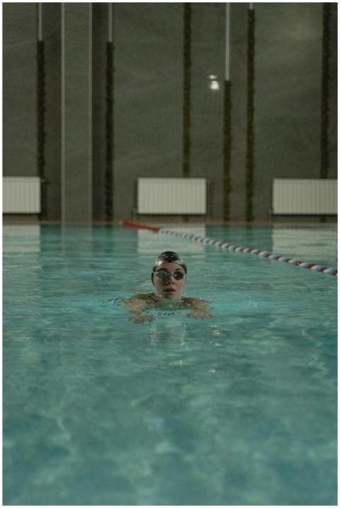 Person swimming in an indoor pool with goggles and