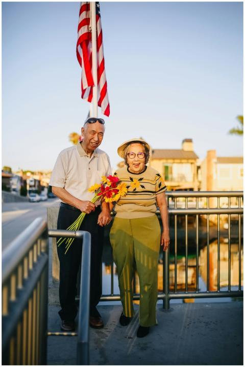 Joyful elderly Asian couple holding flowers under