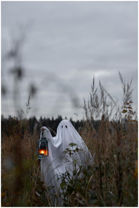 Eerie ghostly figure holding a lantern in a misty
