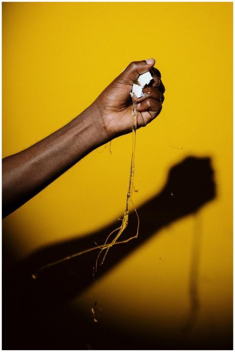 Close-up of a hand squeezing an egg with shadow ag