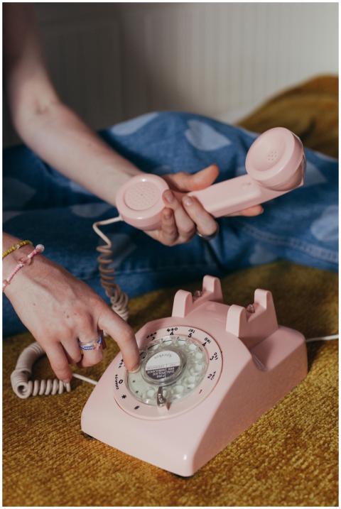 Close-up of a vintage pink rotary phone being dial