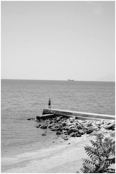 A solitary figure stands on a pier overlooking the