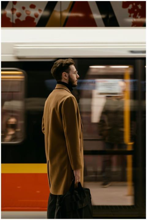 Man standing at subway platform with train moving