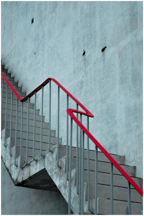Concrete staircase with a striking red handrail ou