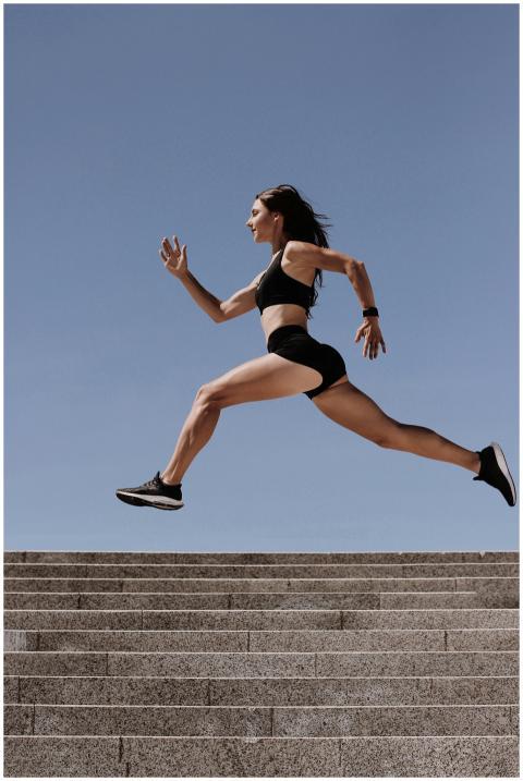 Energetic woman in active wear jumping on stairs o