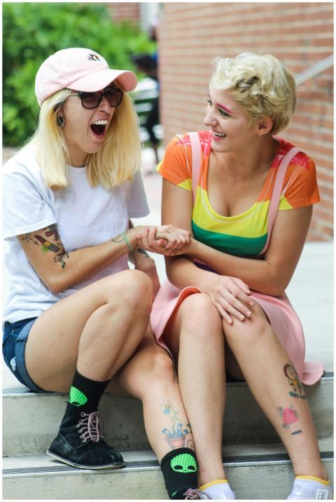 Two happy friends sitting outdoors, sharing a laug