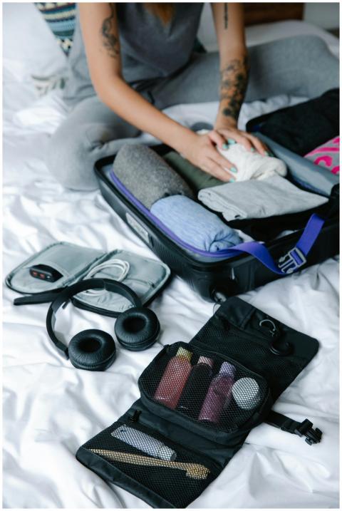 Person organizing suitcase with clothes and toilet