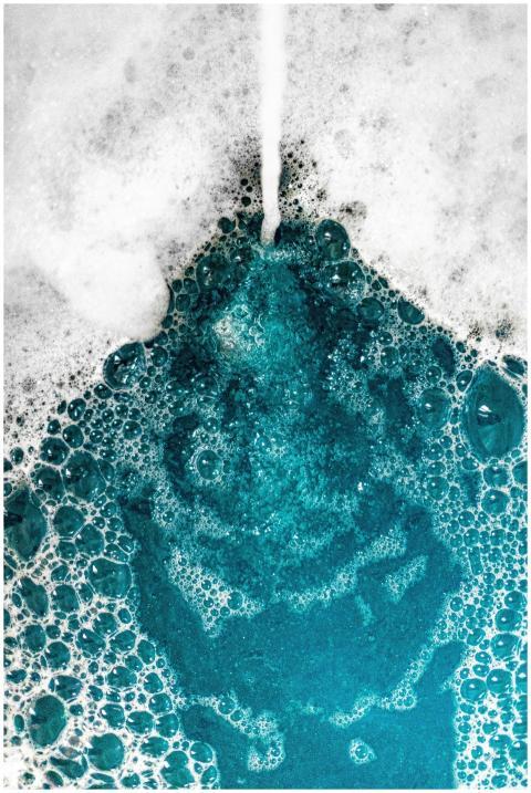 Close-up of blue foam bubbles merging with water,