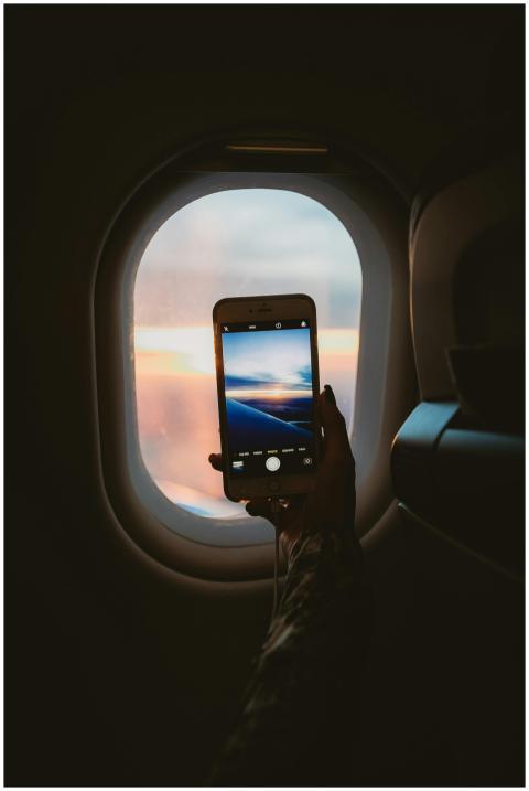 A person takes a photo of a sunset through an airp
