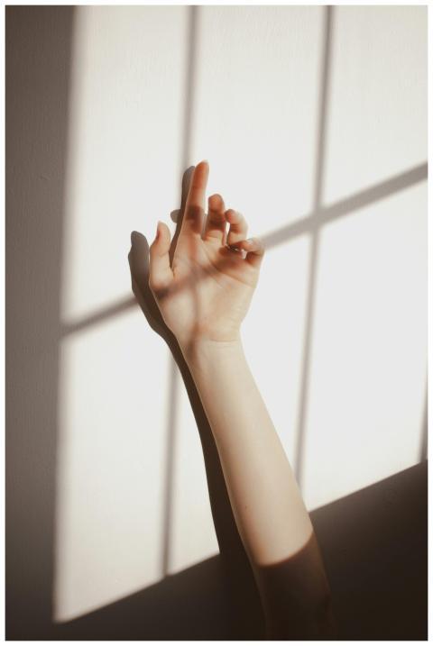 Crop anonymous female keeping raised hand against